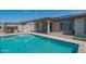 Inviting backyard pool surrounded by manicured turf, a brick patio, and solar panels above at 18925 W Windsor Blvd, Litchfield Park, AZ 85340
