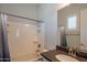 Bathroom with shower-tub combo, dark countertop, brushed bronze faucet, and window with shutter at 18925 W Windsor Blvd, Litchfield Park, AZ 85340