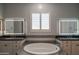 A luxurious bathroom featuring a soaking tub, double sinks, and illuminated mirrors for a spa-like experience at 18925 W Windsor Blvd, Litchfield Park, AZ 85340