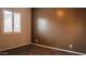 Cozy bedroom with neutral carpet, a brown accent wall, and a window with bright white shutters at 18925 W Windsor Blvd, Litchfield Park, AZ 85340