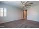 A bright carpeted bedroom with a ceiling fan and a view of a hallway at 18925 W Windsor Blvd, Litchfield Park, AZ 85340