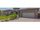 View of the home's exterior highlighting the driveway, two-car garage, and desert landscaping at 18925 W Windsor Blvd, Litchfield Park, AZ 85340