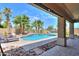 A beautiful backyard pool view from under the covered patio, surrounded by palm trees and a rock landscape at 22338 N O Sullivan Dr, Maricopa, AZ 85138