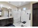 Bright bathroom featuring dark cabinets, dual shower heads and a shower bench in the shower at 23830 W Romley W Ave, Buckeye, AZ 85326