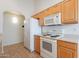 Efficient kitchen featuring wooden cabinets, a white refrigerator, and cooking range at 2439 W White Feather Ln, Phoenix, AZ 85085