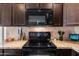 Close-up of kitchen with black appliances, granite countertops, stone backsplash, and dark wood cabinetry at 2748 W Sunland Ave, Phoenix, AZ 85041