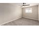 This bedroom features a ceiling fan, neutral paint, a large window, and gray carpet at 5208 W Earll Dr, Phoenix, AZ 85031