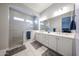 Modern bathroom featuring a double sink, white cabinets, and a glass shower with tiled walls at 5621 N 189Th Dr, Litchfield Park, AZ 85340