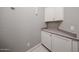 This laundry room features white tile flooring and white cabinets with countertops at 5621 N 189Th Dr, Litchfield Park, AZ 85340