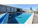 Sparkling pool with travertine tile border, basketball hoop, and covered patio for outdoor relaxation and entertainment at 5621 N 189Th Dr, Litchfield Park, AZ 85340