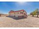 Home exterior featuring a three-car garage, desert landscaping, and neutral stucco with red trim at 6431 N 418Th Ave, Tonopah, AZ 85354