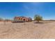 Desert home featuring a red-trimmed roof, neutral stucco, and desert landscaping under a blue sky at 6431 N 418Th Ave, Tonopah, AZ 85354