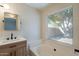 Bright bathroom featuring a wood vanity, soaking tub and a large window with backyard views at 6718 E Northridge St, Mesa, AZ 85215