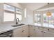 Modern kitchen showcasing white cabinetry, countertops, stainless steel sink, faucet and a bright window at 6718 E Northridge St, Mesa, AZ 85215