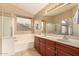 Bright bathroom featuring double sinks, cherry wood cabinets, and a separate tub and shower at 700 W Gascon Rd, San Tan Valley, AZ 85143