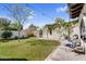 The grassy backyard has manicured landscaping, mature trees, and a white stucco wall at 718 E Tuckey Ln, Phoenix, AZ 85014