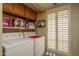 Well-lit laundry area with white appliances, upper cabinets, and a window with shutter blinds at 8651 E Royal Palm Rd # 206, Scottsdale, AZ 85258