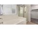 Bright bathroom featuring a tub and glass-enclosed shower, and window with white shutters at 9212 W Salter Dr, Peoria, AZ 85382