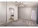 A spacious bedroom with neutral walls, gray carpet with entrance to bathroom and doorway at 9212 W Salter Dr, Peoria, AZ 85382
