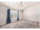 A spacious bedroom with neutral walls, gray carpet and a ceiling fan with a window and curtains at 9212 W Salter Dr, Peoria, AZ 85382