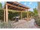 Charming backyard grilling station featuring a stainless steel grill under a rustic wooden pergola surrounded by lush greenery at 9445 N 106Th St, Scottsdale, AZ 85258