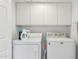 Efficient laundry room with a side-by-side washer and dryer setup and overhead cabinets for organized storage at 9445 N 106Th St, Scottsdale, AZ 85258