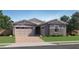 Charming single-story home featuring a brick driveway, a gray exterior, and a two-car garage at 974 W Saddle Run, Apache Junction, AZ 85120