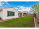 A large grassy backyard with a block fence, a covered patio and desert landscaping at 9823 E Red Giant Dr, Mesa, AZ 85212