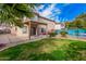 A verdant backyard features a covered patio and view of a turquoise pool at 11023 E Florian Ave, Mesa, AZ 85208
