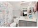 Bathroom with a toilet, shower with patterned curtain, sink, and gray cabinets at 11813 W Sierra St, El Mirage, AZ 85335