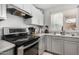 Well-lit kitchen featuring stainless steel appliances, light gray cabinets, and a sink under a window at 11813 W Sierra St, El Mirage, AZ 85335