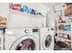 Bright laundry room features a white washer and dryer with shelf storage and laundry supplies at 11813 W Sierra St, El Mirage, AZ 85335
