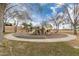 Community playground with modern play equipment surrounded by mature trees and circular sidewalk at 1312 N Joplin Cir, Mesa, AZ 85207