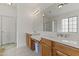 Bright bathroom featuring double sinks with wood cabinets and a large mirror, complemented by tile flooring at 15469 W Dreyfus St, Surprise, AZ 85379