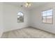 Cozy bedroom featuring neutral carpet, a ceiling fan, and two windows providing natural light and neighborhood views at 15469 W Dreyfus St, Surprise, AZ 85379