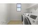 Laundry room featuring a modern washer and dryer, tile flooring, and a window at 15469 W Dreyfus St, Surprise, AZ 85379