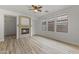 Living room with a beige fireplace, windows, ceiling fan, and light wood floors at 15469 W Dreyfus St, Surprise, AZ 85379