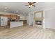 Open concept living room with a kitchen island, fireplace, ceiling fan, and light wood floors at 15469 W Dreyfus St, Surprise, AZ 85379