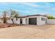 Single-story stucco home featuring a black garage door, desert rock landscaping, and an arched front door entrance at 18060 N 24Th Dr, Phoenix, AZ 85023