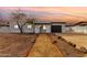 Inviting single-story home with desert landscaping, complemented by a black garage door, and arched entryway at sunset at 18060 N 24Th Dr, Phoenix, AZ 85023