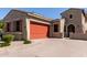 Charming single-Gathering home featuring a brick driveway, desert landscaping and a striking orange garage door at 1933 N 140Th Ave, Goodyear, AZ 85395