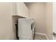 Well-lit laundry room features a full-size white washer and dryer set and upper storage cabinets at 1933 N 140Th Ave, Goodyear, AZ 85395