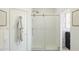 Bright bathroom featuring a glass-enclosed shower with sliding door, white tiles, and a door with a robe hanging on the back at 20301 W Turney Ave, Buckeye, AZ 85396