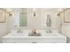 Stylish bathroom showcasing double vanity with white countertops, framed mirrors, modern sconces, and a glimpse of the glass-enclosed shower at 20301 W Turney Ave, Buckeye, AZ 85396