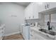 Modern laundry room with white cabinets, marble countertops, and stainless-steel sink and appliances at 2040 W Gail Rd, Queen Creek, AZ 85142