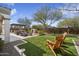 Backyard with travertine patio, outdoor fireplace, seating area, putting green, and mature desert landscaping at 22410 N 29Th Pl, Phoenix, AZ 85050