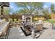 Outdoor fireplace with travertine patio, lounge seating, built-in bar, and desert landscaping at 22410 N 29Th Pl, Phoenix, AZ 85050
