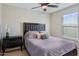 Cozy bedroom with a padded headboard, dark wood dresser, and window with natural light at 29243 N 122Nd Ln, Peoria, AZ 85383