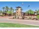 Welcoming community entrance featuring lush landscaping, a tower, and flagpoles with the American and Arizona flags at 29243 N 122Nd Ln, Peoria, AZ 85383