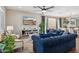 Bright living room showcasing blue sofas, a ceiling fan, and sliding glass doors to the outdoor patio at 29243 N 122Nd Ln, Peoria, AZ 85383